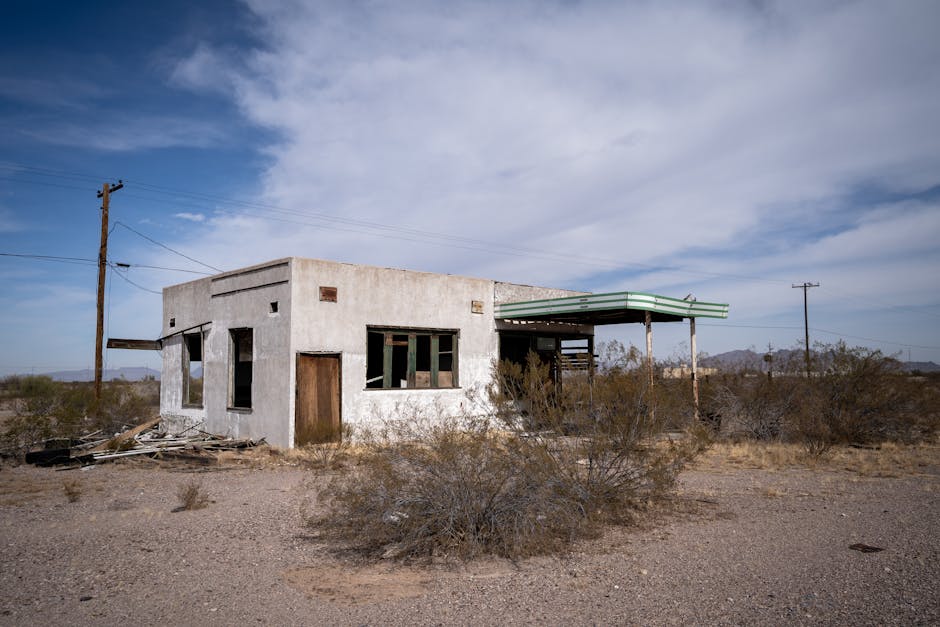 Desolate landscape with an abandoned building under a bright blue sky in Arizona, USA.